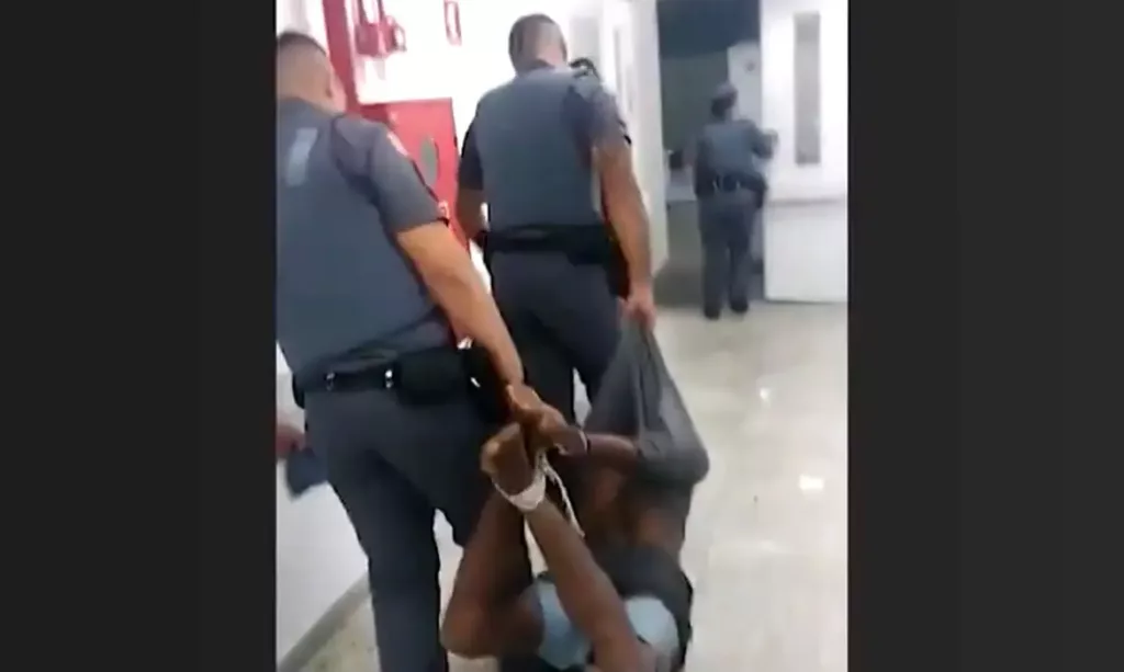 Policiais carregando pessoa amarrada por cordas