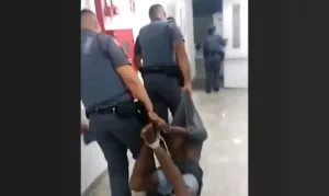 Policiais carregando pessoa amarrada por cordas